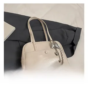 Detail of cream white Boston bag with matte leather finish and silver bow heart charm