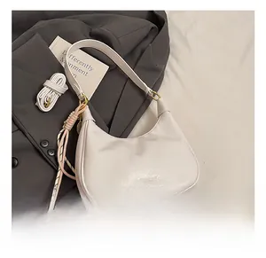 Close-up of white wax leather hobo bag with woven tassel and detachable shoulder strap