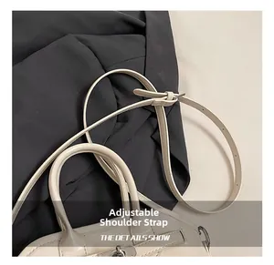 Close-up of cream leather bag featuring adjustable shoulder strap and metal turn-lock clasp