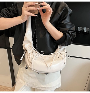 Détail du sac croissant en cuir verni blanc avec cordon de serrage et nœud élégant