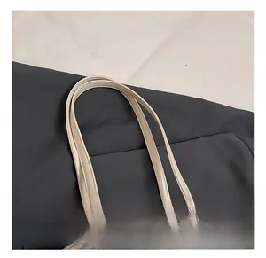 Close-up of comfortable double handles and metal D-ring on cream white leather tote bag