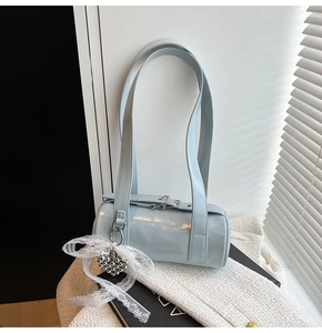 Detail view of light blue baguette bag with silver heart charm and white lace bow