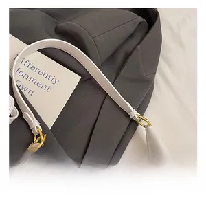 Close-up of white pebble leather tote bag with gold metal rings and braided handle details