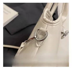 Detail view of premium cream shell bag featuring glossy leather and silver metal hardware