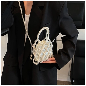 Détail d'un mini sac en perles blanches fait main porté sur un blazer noir contrastant