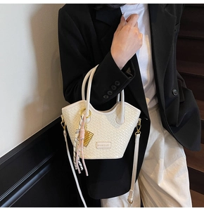 Détail du sac à main tissé avec breloque dorée et bandoulière beige amovible