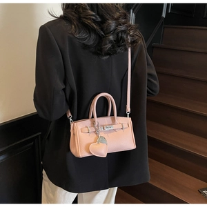Macro view of pink lychee leather handbag with silver lock and heart charm detail