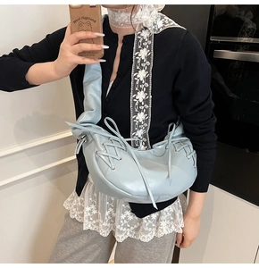 Détail de la bandoulière plissée bleu clair et du laçage croisé sur le sac