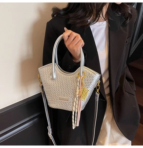 Détail du sac seau argenté tressé avec foulard rayé et pendentif boulier doré
