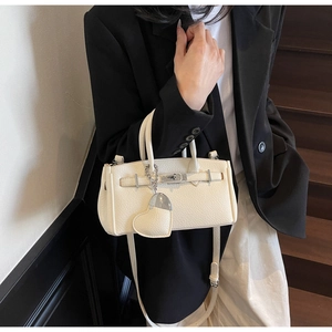Detail of lychee pattern leather bag with silver buckle and heart pendant in cream white
