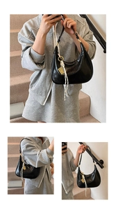 Detail of black wax leather half-moon bag with braided rope and gold shield charm accessory