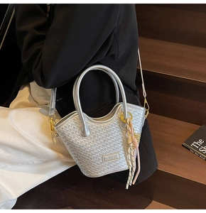Détail du sac à main tissé argenté avec finition métallique et pendentif à pompon décoratif