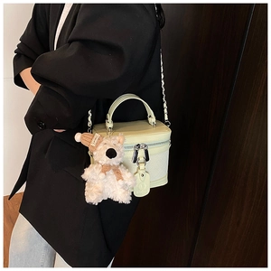 Detail of pistachio green box bag with plush bear charm and metal chain strap