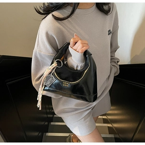 Detail view of black oiled leather dumpling bag with gold logo and tennis racket charm