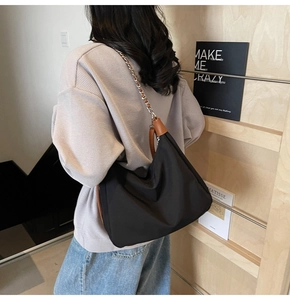 Seitenansicht einer schwarzen Nylon-Tasche mit Kettenriemen am Modell in Bibliothek