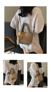 Detailed macro view of brown lychee grain texture and bear charm on bucket handbag