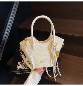 Détails du sac seau tissé beige crème avec ferrures dorées et breloque décorative