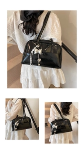 Detail of black glossy patent leather Boston bag featuring metallic bow and heart charms
