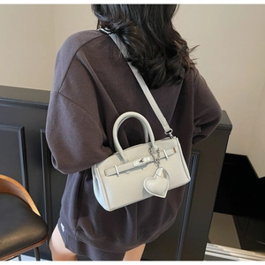 Detail of light grey lychee leather handbag with silver lock and heart pendant
