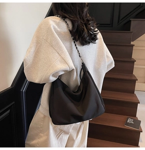 Detail der minimalistischen schwarzen Nylon-Hobo-Tasche mit Leder- und Metallkettenriemen