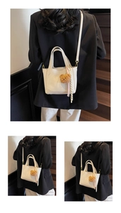 Close-up of cream leather bucket bag texture with gold logo and plush bear charm detail
