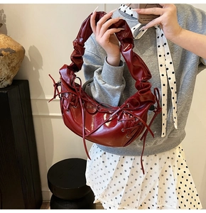 Détail du sac lune bordeaux brillant avec poignée froncée et nœud de serrage latéral