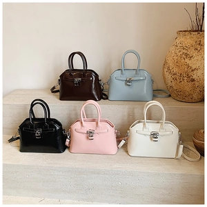 Collection of leather shell bags in five colors displayed on elegant stone stairs
