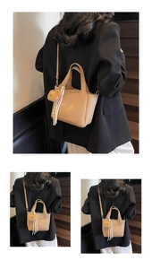 Detail view of beige lychee texture bucket bag with plush bear and striped scarf