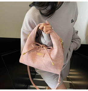 Detail of pink faux suede handbag with decorative bow and golden brand logo plaque