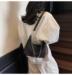 Details einer schwarzen Nylon-Unterarmtasche mit silberner Kette und verstellbarem Gurt