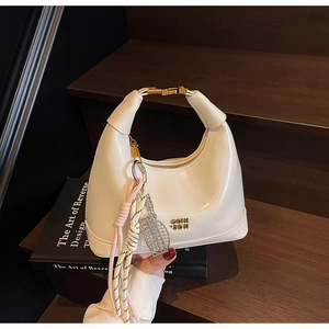 Detailed macro view of white oil wax leather handbag with golden hardware and rope charms