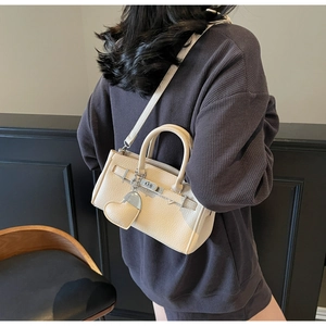 Beige lychee pattern leather crossbody bag with silver buckle worn by a model
