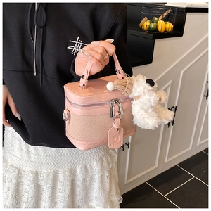 Pink vanity box bag featuring woven leather texture and a plush bear charm detail