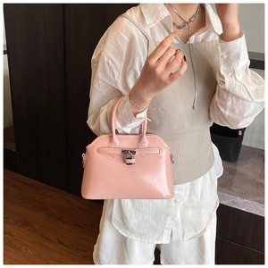 Detail of pink glossy patent leather shell bag with metallic lock and rounded handle