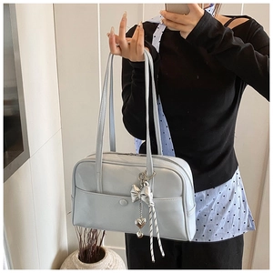 Close-up of light blue leather Boston bag with silver bow and heart charm details
