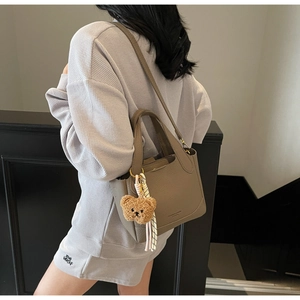 Taupe lychee textured bucket bag with a cute brown plush bear charm detail