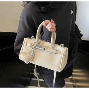 Detail of off-white lychee pattern handbag with silver chain and heart charm