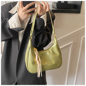 Detail of avocado green hobo bag with woven charm and golden zipper closure