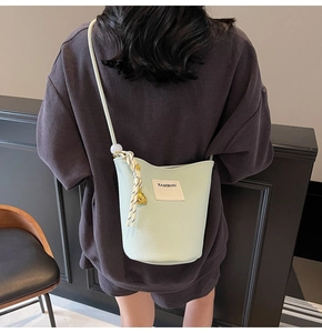 Détail du sac seau vert clair texturé litchi avec breloque tissée et pendentif ours