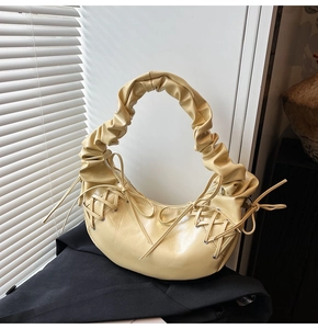 Détail du sac hobo jaune crème avec poignée plissée et détails de laçage à œillets argentés