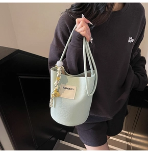 Détail du sac seau vert menthe clair à texture litchi avec un pendentif en métal
