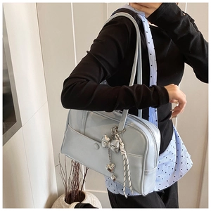 Detail of light blue shoulder bag with silver bow charm and heart pendant decoration