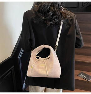 Detail of minimalist cream handbag with soft texture, metal logo and drawstring detail