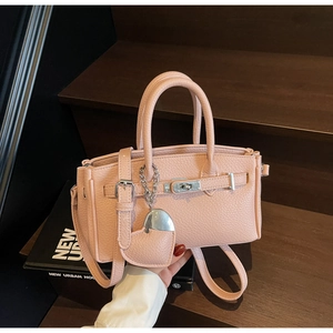 Detailed macro view of pink litchi grain leather mini handbag with a classic metal twist lock