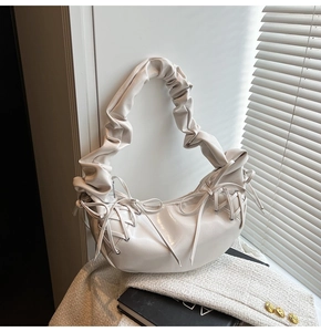 Détail du sac à bandoulière blanc avec poignée froncée et lacets latéraux décoratifs
