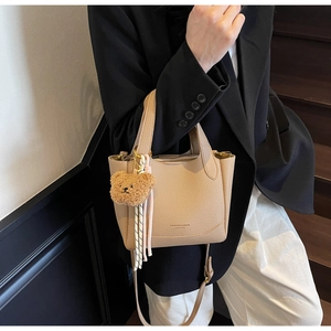 Close-up of litchi pattern leather bucket bag with bear charm and adjustable strap