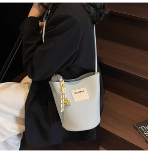 Détail du sac seau bleu clair avec grain litchi et pendentif décoratif en corde tissée