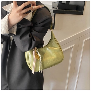 Detail of green tote bag with pleated leather texture and decorative woven cord charms
