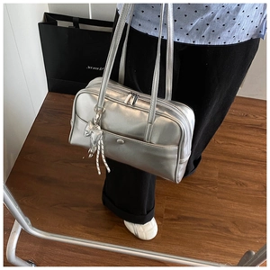 Detail of silver oil wax leather Boston bag featuring chic bow and woven rope pendants