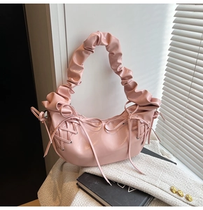 Détail du sac à bandoulière froncé rose avec nœuds latéraux et texture brillante